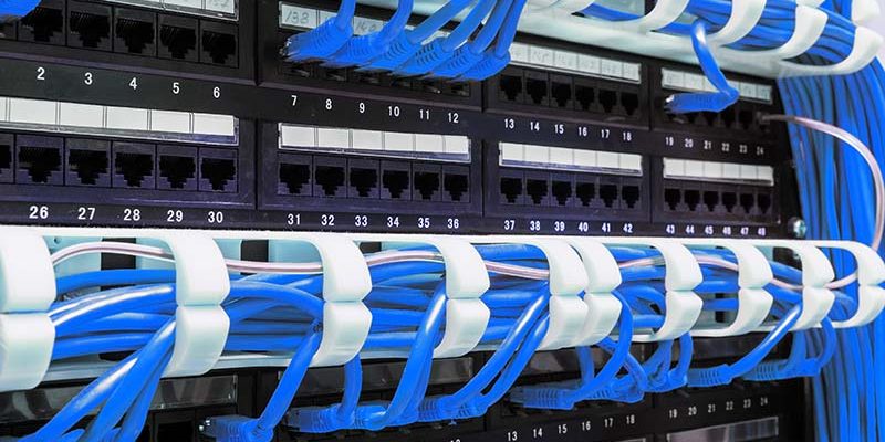 Close up of blue network cables connected to black patch panel